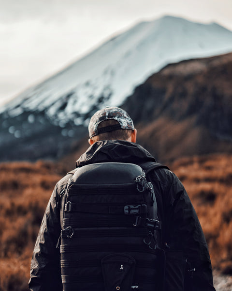 view of a man from behind walking towards a mountain with a backpack on