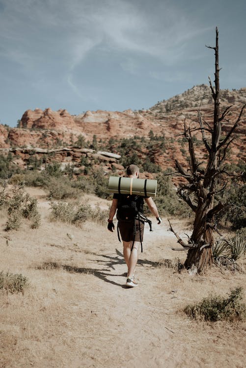 man walking through desert Southwest with a backpack and sleeping pad