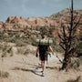 man walking through desert Southwest with a backpack and sleeping pad